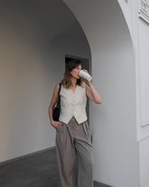 a lady wears a beige suit vest with gray suit pants